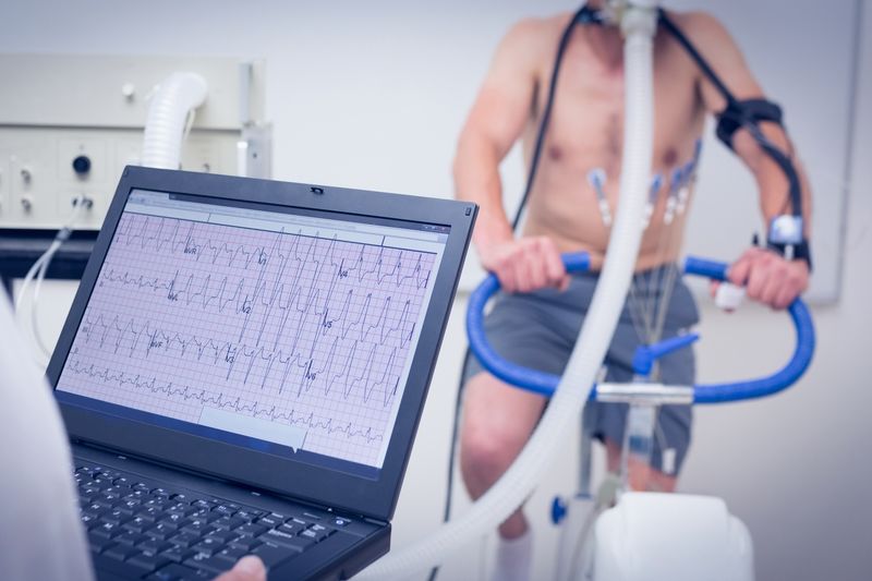 Laptop displaying diagnostic information while man rides an exercise bike in the background