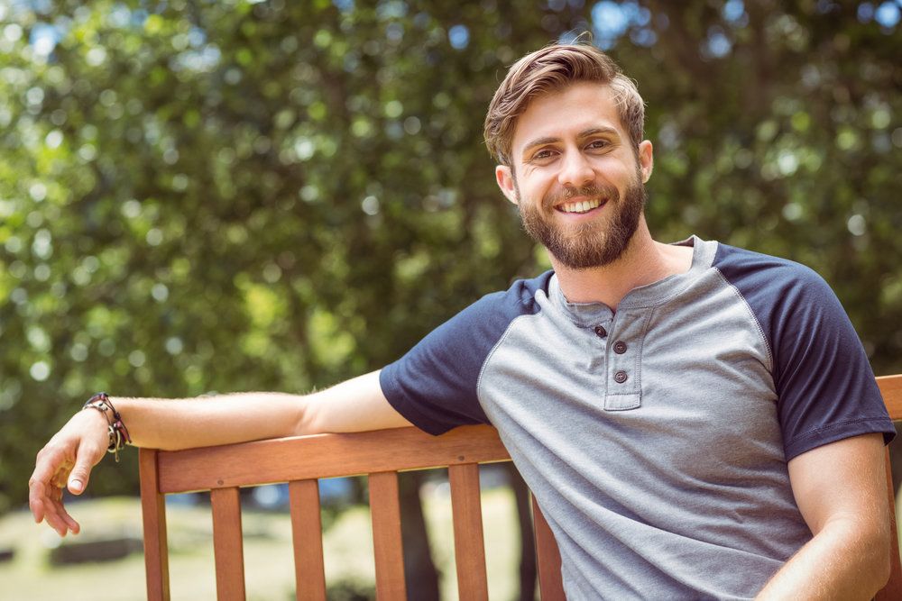 Smiling man sitting on a park bench